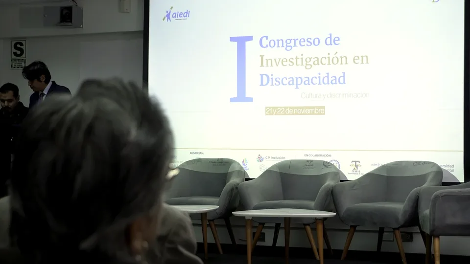 Escenario del Congreso de Investigación en Discapacidad con pantalla principal y sillones preparados para la mesa.