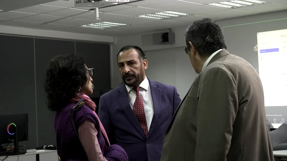 Tres asistentes conversan de pie al finalizar una actividad en una sala del congreso.