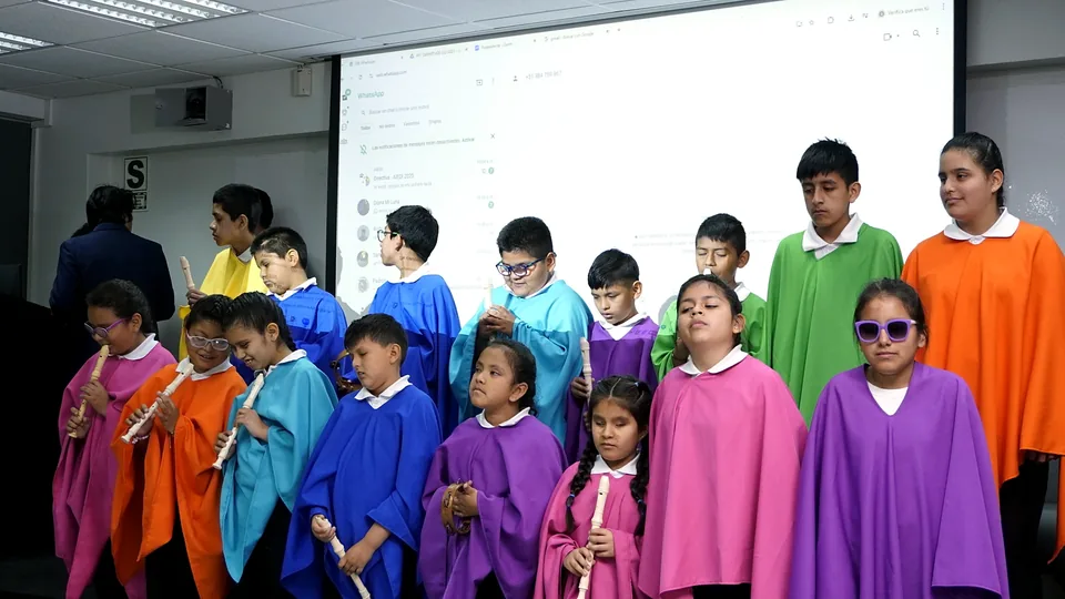 Grupo de niños y adolescentes participa en una presentación artística o actividad escénica con capas de colores.
