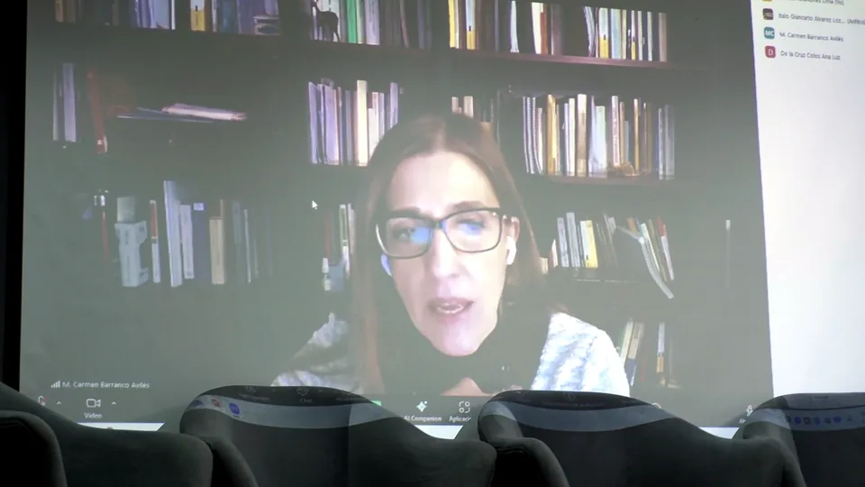 Participante remota aparece por videollamada proyectada en la pantalla del auditorio.
