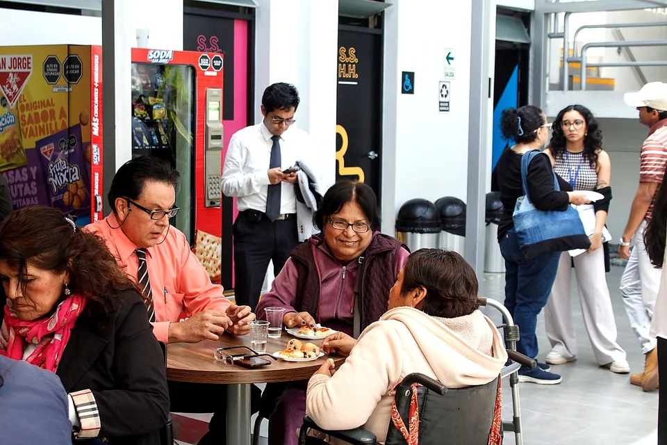 Asistentes conversan alrededor de una mesa con refrigerios durante una pausa del congreso en el patio interior.